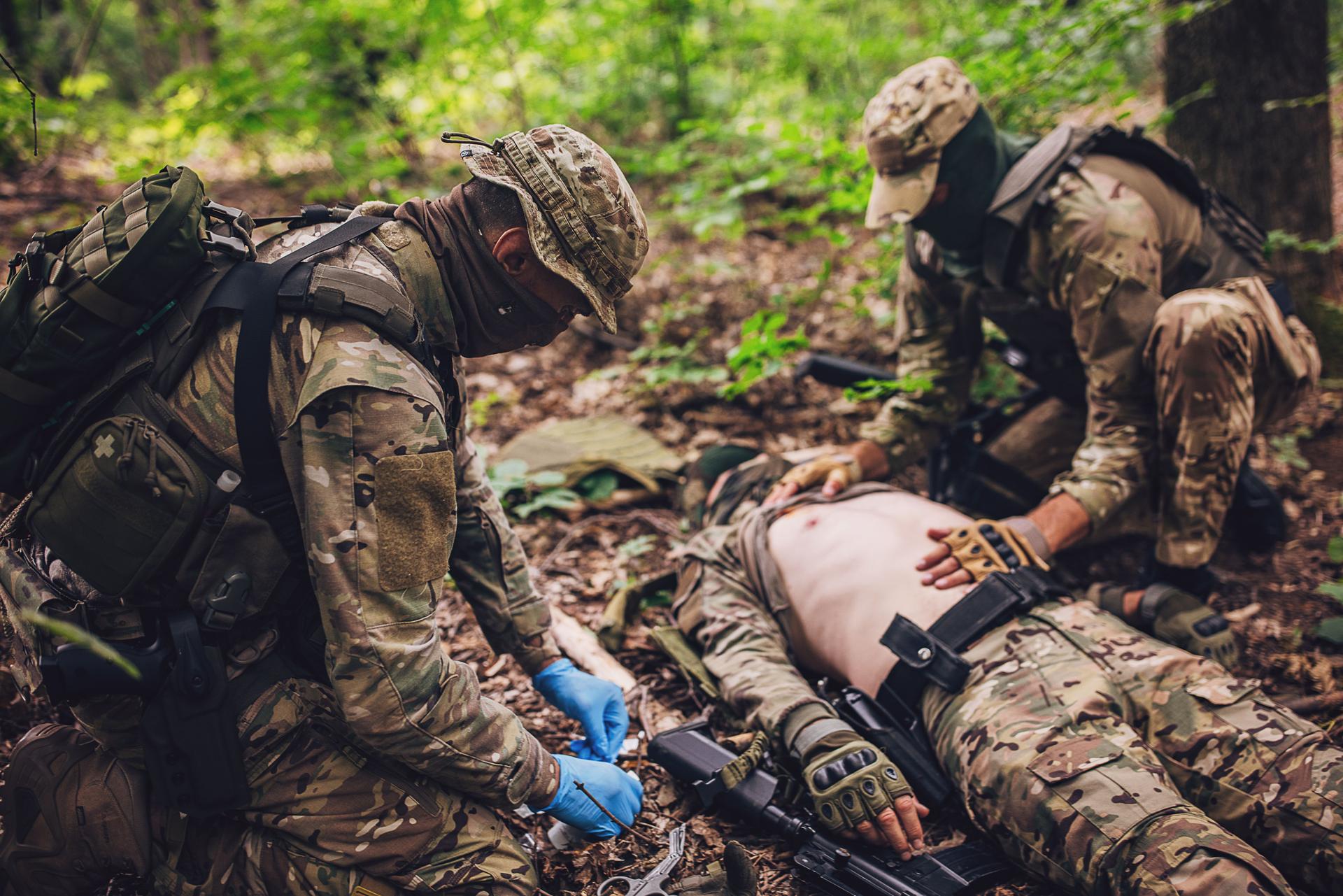 Soldiers providing first aid in a forest environment